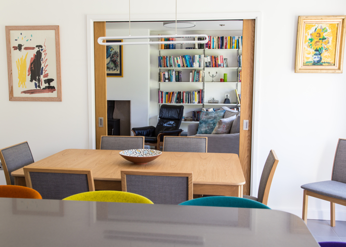 Contemporary oak dining table with pocket doors leading into living room with modern book cases