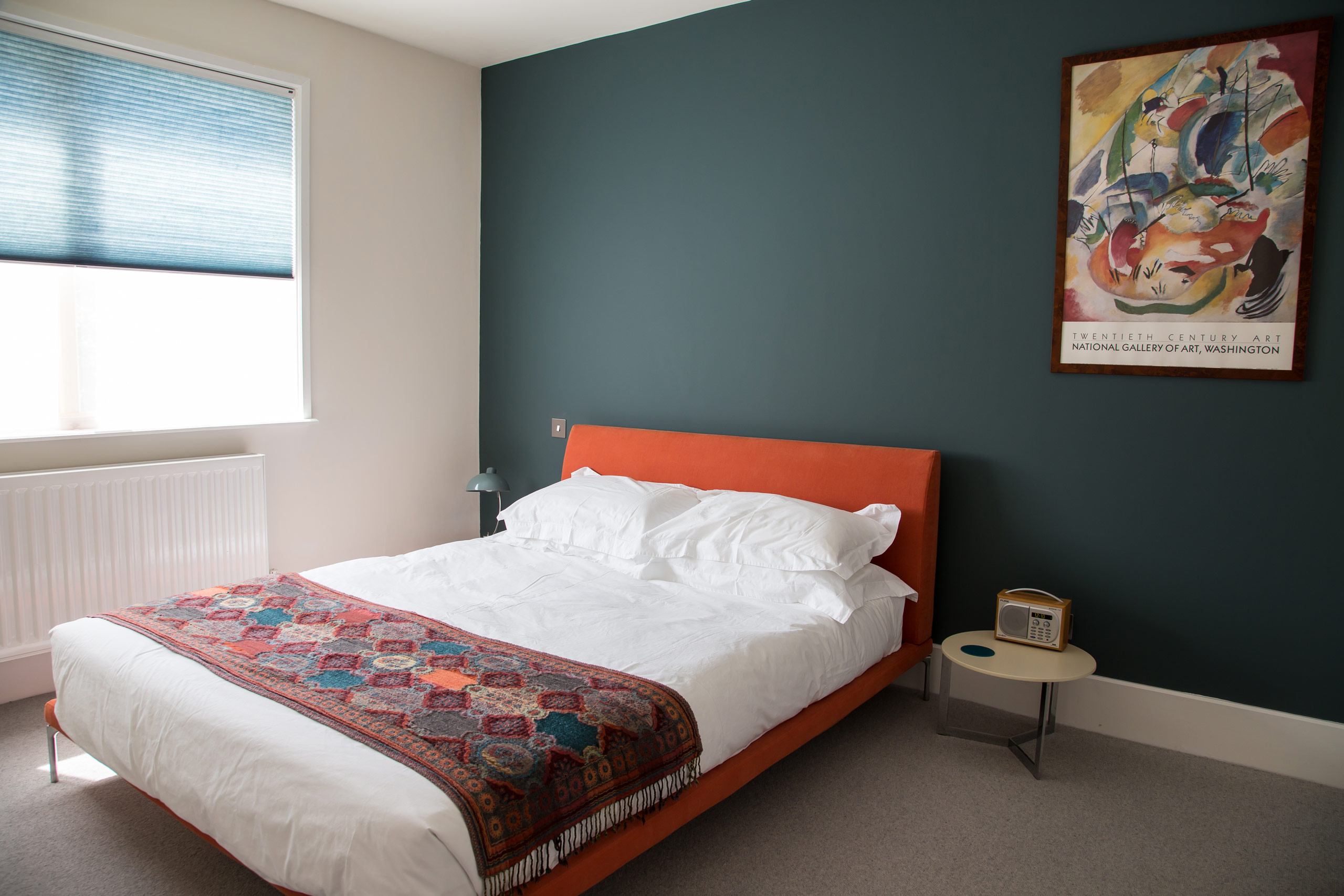 Bedroom with orange upholstered bed and dark wall