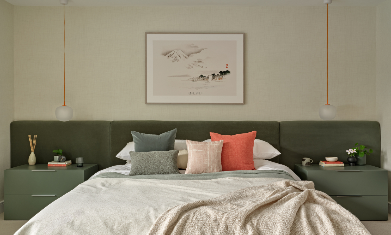 Wall to wall upholstered smooth velvet headboard and bed in dusty green with contemporary pendant bedside lights and green low bedside draweres